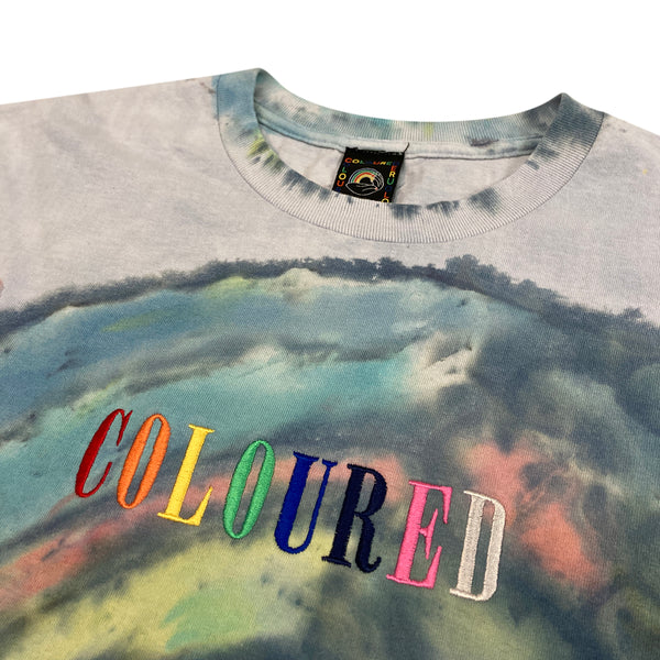 An image of a gray t-shirt with the Coloured Publishing logo dyed and "COLOURED" embroidered in rainbow colors.