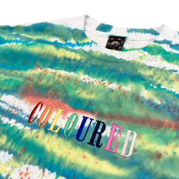 An image of a white t-shirt with dyed colorful stripes and "COLOURED" embroidered in rainbow colors.