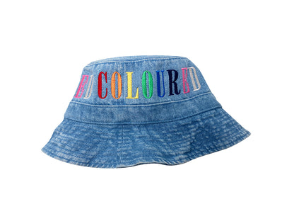 Image of a light denim bucket hat with "COLOURED" embroidered in rainbow letters.